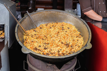 Rice with meat, carrots in big cauldron, traditional dish of pilaf, national cuisine.