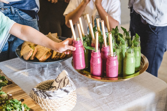 A hand takes a smoothie bottle among other people