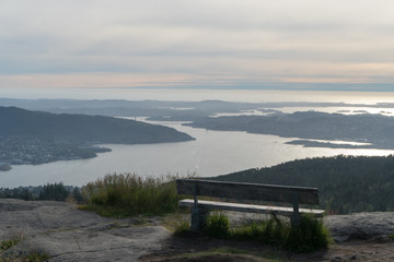 Mountain Top view of islands surrounding Bergen, Norway, with a bench in the foreground at sunset