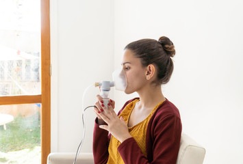 Young woman doing inhalation nebulizer in hospital, holding a mask nebuliser inhaling asthma and...