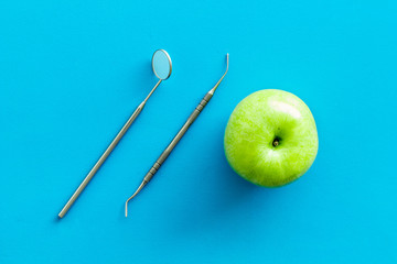stomatologist mirror and apple on blue doctor's office desk background top view