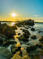 sunset at Corona del Mar State Beach CA USA with great view of the ocean, sun, stone formation, and light