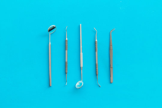 Dentist work desk with tools for teeth on blue background top view