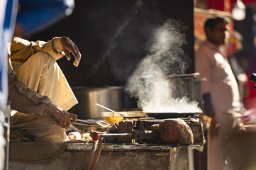 An Indian elderly man is cooking Chapati on the streets of Jaipur, Rajasthan, India. Chapati is an...