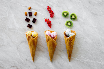 Gelato in waffle cone with kiwi, hazelnut, chocolate and wineberry on marble backgroung top view