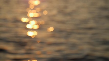 Out of focus, sun beam reflection on calm water surface in evening, golden hour. Slow motion.Close up.