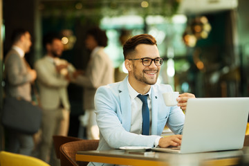 Young businessman uses a laptop in a cafe