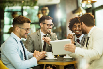 Men are sitting at table in modern cafe. Talk about work