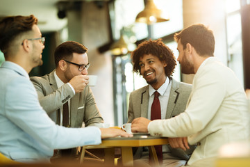 Men are sitting at table in modern cafe. Talk about work