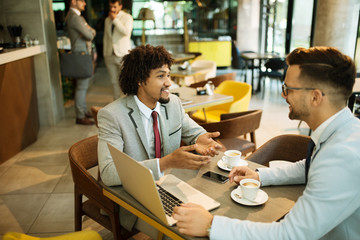 Men are sitting at table in modern cafe. Talk about work