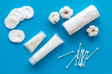 Hygiene cotton swabs, pads and cream for pattern on blue background top view