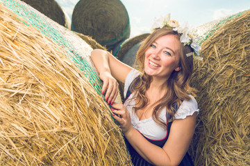 Bayerische Frau im Dirndl vor einem strohballen Oktoberfest Theme