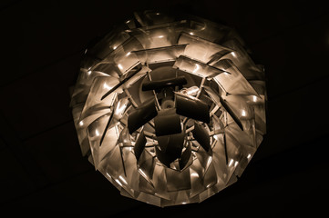 White pinecone-shaped chandelier suspended from the ceiling and lit from within creates an abstract shot.