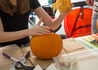 Process of carving pumpkin to make Jack-o-lantern. Creating traditional decoration for Halloween and Thanksgiving. Cutted orange pumpkin lay on table in woman hands.