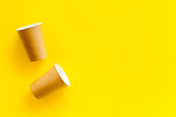 Paper cups for coffee to go on yellow background top view mockup