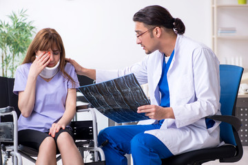 Obraz premium Young woman in wheel-chair visiting male doctor