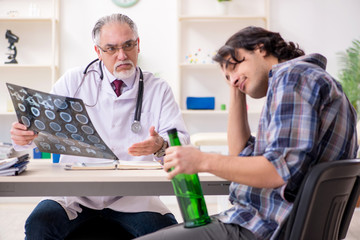 Obraz premium Young male alcoholic visiting old doctor