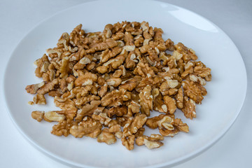 A white plate with peeled walnut kernel, close-up, top view, side view.