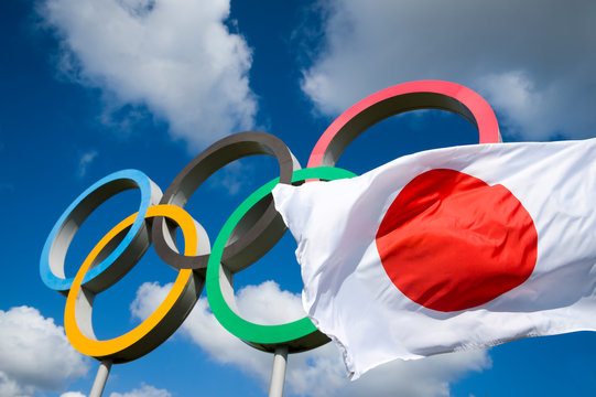 LONDON - APRIL 19, 2019: A Japanese flag flutters in the wind in front of Olympic Rings standing under bright blue sky.
