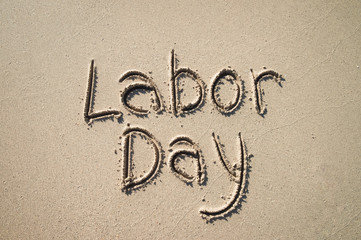 Simple Labor Day message handwritten on the smooth sand of an empty beach