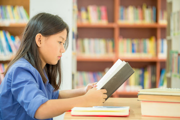 Portrait of clever student with open book reading it in college library