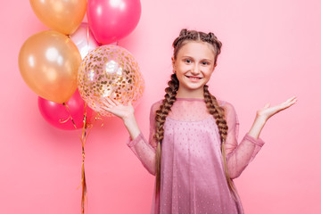 Obraz na płótnie Canvas Happy and beautiful teen girl holding a bunch of colorful balloons and looking at camera with smile on pink background