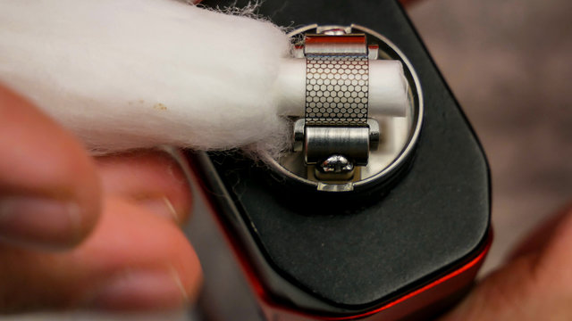 Preparation of mesh coil in the atomizer for vaping - Inserting the cotton under the coil.