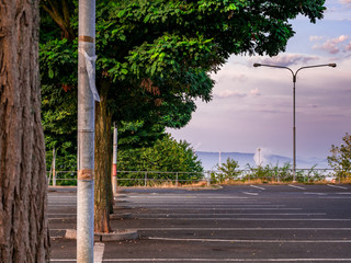 Fototapeta premium An empty parking lot with trees and a view of the city covered in a foggy morning