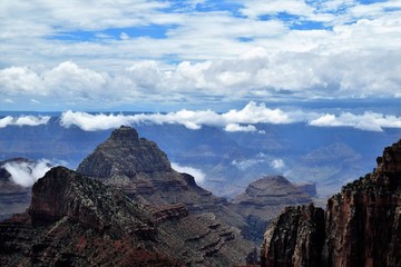 Fototapeta premium Blue Cloudy Skies Highlight Dark Stony Formations at North Rim of Grand Canyon