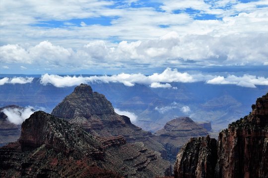 Blue Cloudy Skies Highlight Dark Stony Formations at North Rim of Grand Canyon