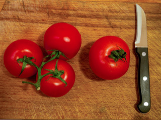 Tomatoes with a knife on a wooden background