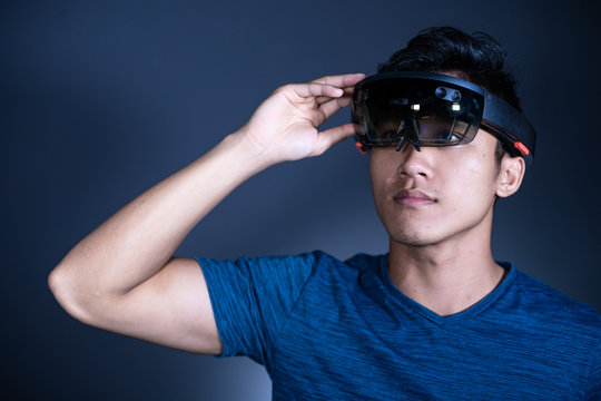 The Asian young man with virtual reality glasses. Experience VR hololens headset in studio with advanced technology.