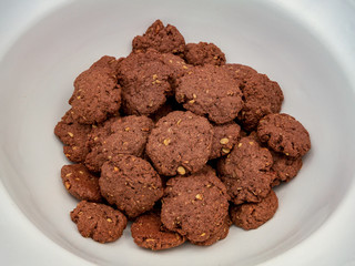 Chocolate homemade cookies with nuts, on a pile in a large white bowl