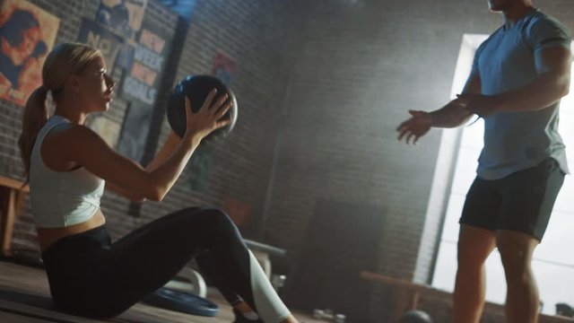 Beautiful Young Girl Exercises with Personal Trainer, Doing Sit-ups with Medicine Ball, Throwing Pass Back and Forth. Fit and Strong Couple Workout and Exercising. Slow Motion Ball Tracking Camera
