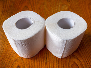 2 rolls of toilet paper stands on a brown wooden table