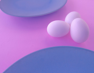 A light blue neutral plate with white chicken eggs on a neutral pink background. Free space to write.