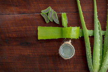 Aloe vera leaves and a glass of water laid on the wooden floor