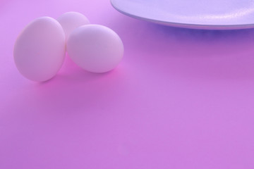A light blue neutral plate with white chicken eggs on a neutral pink background. Free space to write.