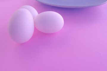 A light blue neutral plate with white chicken eggs on a neutral pink background. Free space to write.