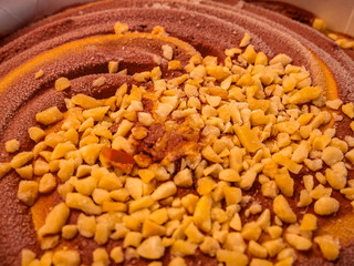 Close-up of sprinkled peanuts on top of twisted chocolate-caramel ice cream in a large bowl - Selective focus