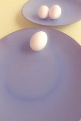 Chicken eggs and a light blue plate on a yellow background. Free space to write. Vegetarian food