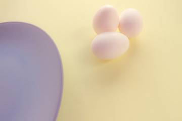 Chicken eggs and a light blue plate on a yellow background. Free space to write. Vegetarian food