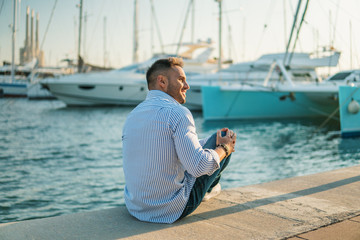 Fototapeta na wymiar Young rich man at Yacht Club. Businessman is Relaxing in the gulf with seaview and luxury ships