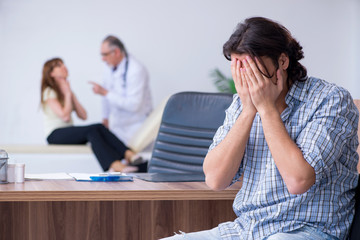 Young couple visiting old male doctor
