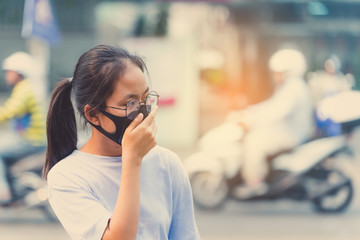 girl wearing a black noses N95 cloth to prevent dust pm 2.5 which has a very high value in a city with traffic