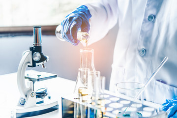 Fototapeta premium Equipment and science experiments oil pouring scientist with test tube yellow making research in laboratory.