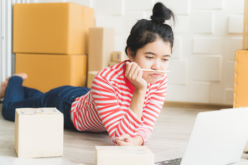 Asian freelance woman working at home and start up small business entrepreneur SME with internet online. Women are preparing products in the packaging box to prepare for delivery to customers.