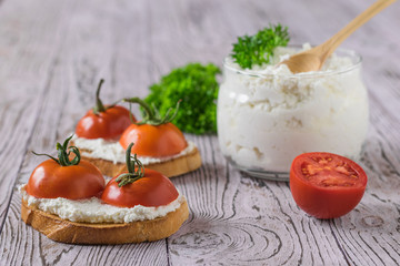 Bread with fresh cottage cheese and cherry tomatoes on a wooden table.