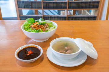 Traditional Vietnamese pork noodle soup with soy sauce on table
