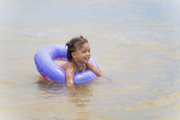 Fototapeta premium Asian pretty baby girl is floating with rubber rings on the beach.